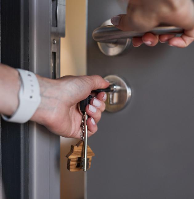 Person öffnet Tür mit Schlüssel